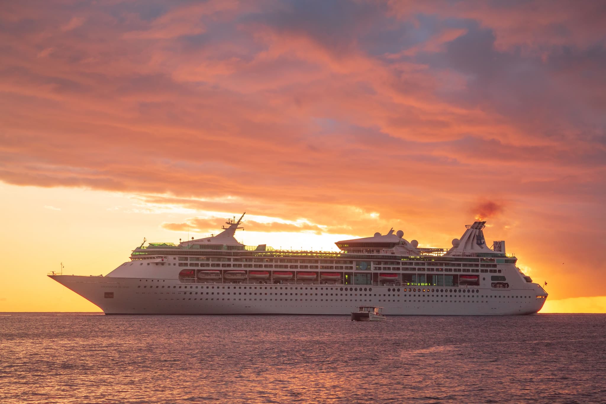 Large luxury cruise ship sailing on calm blue ocean waters at sunset