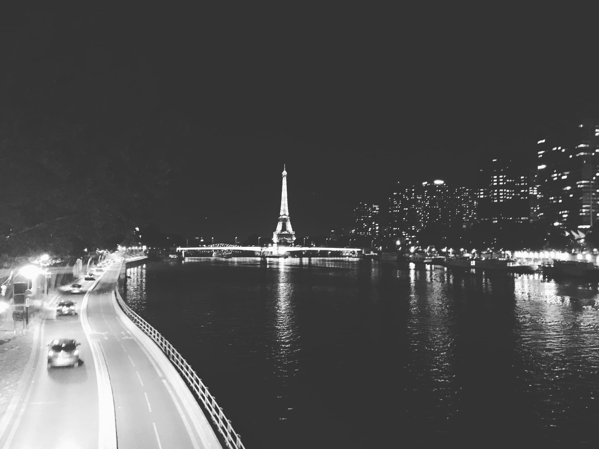Paris Eiffel Tower illuminated at night with Seine River reflections and city lights