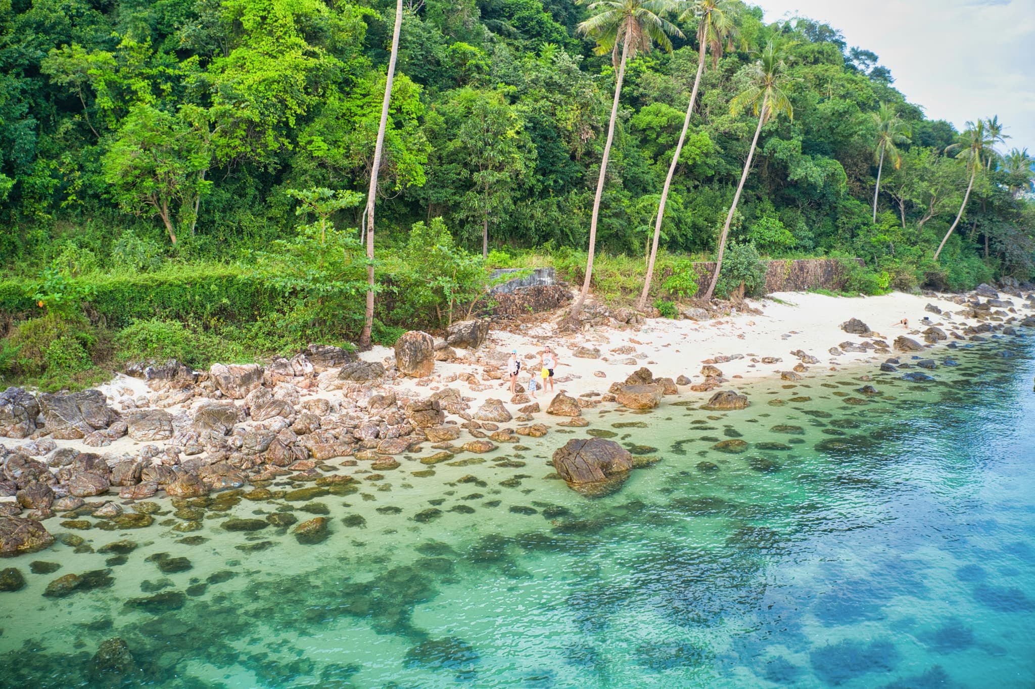 Family enjoying a Thai beach holiday with clear water and white sand