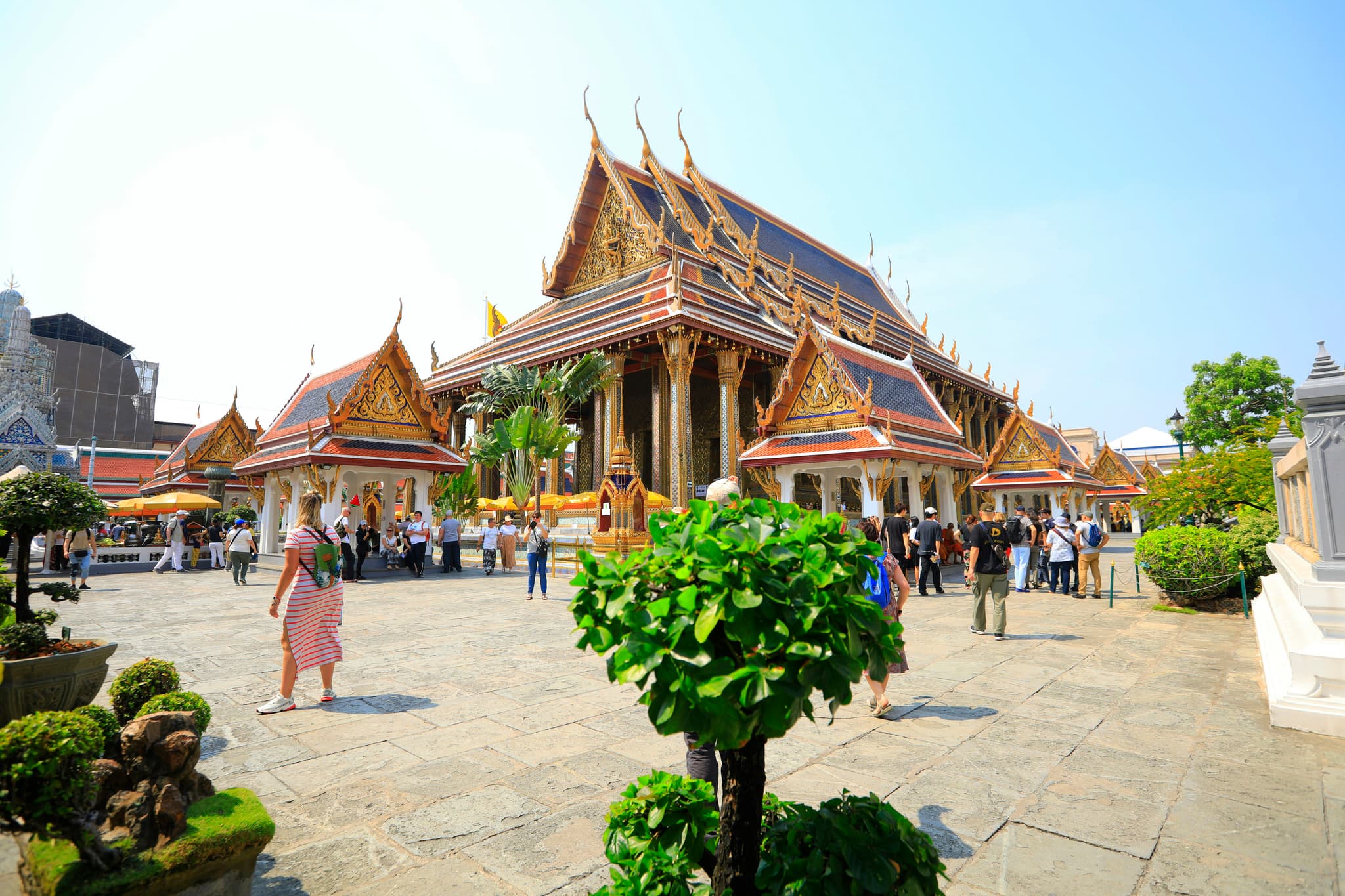 Tourists exploring ornate Thai temple with golden spires