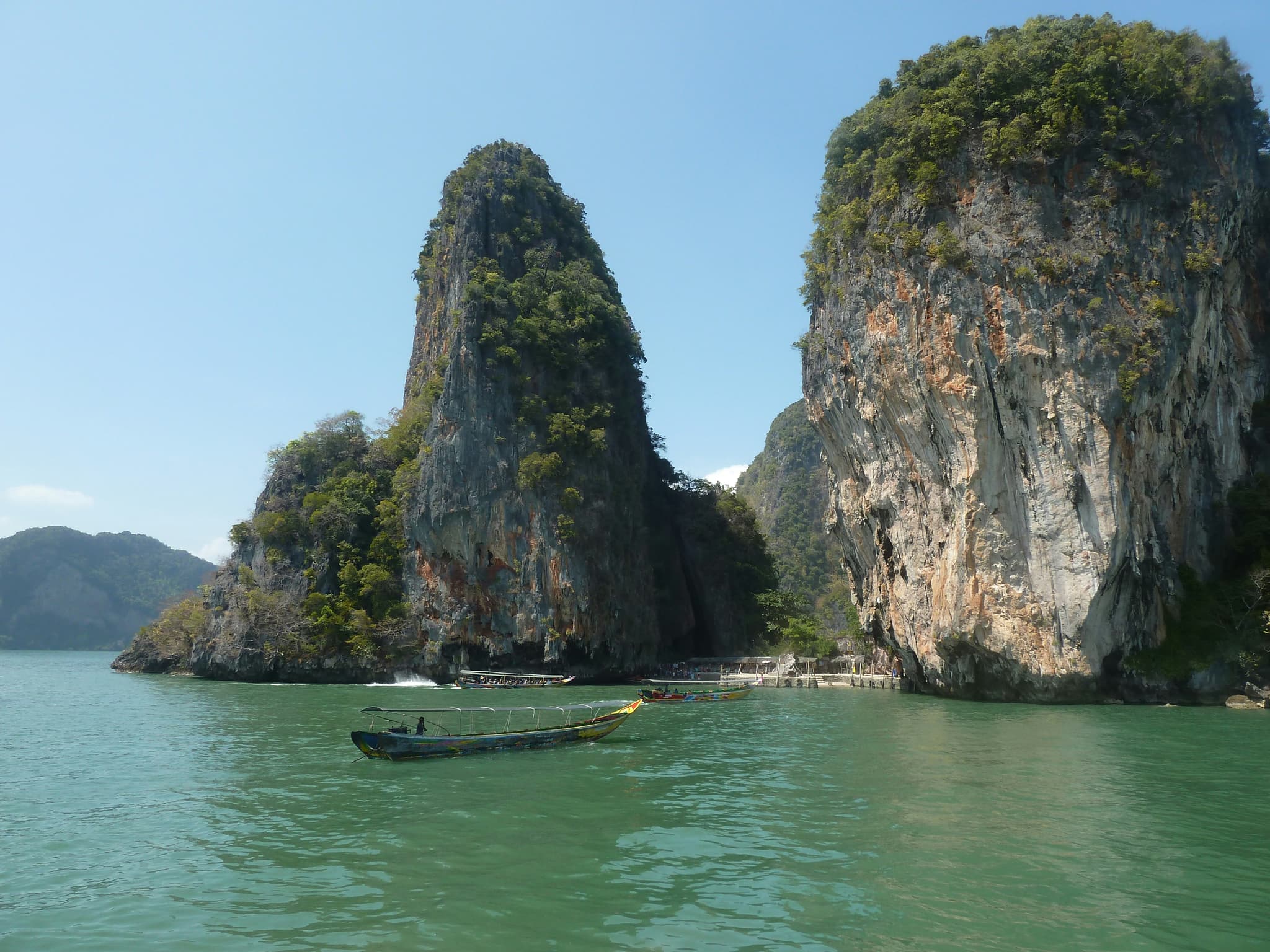 Traditional long-tail boat navigating between Krabi islands with emerald green waters
