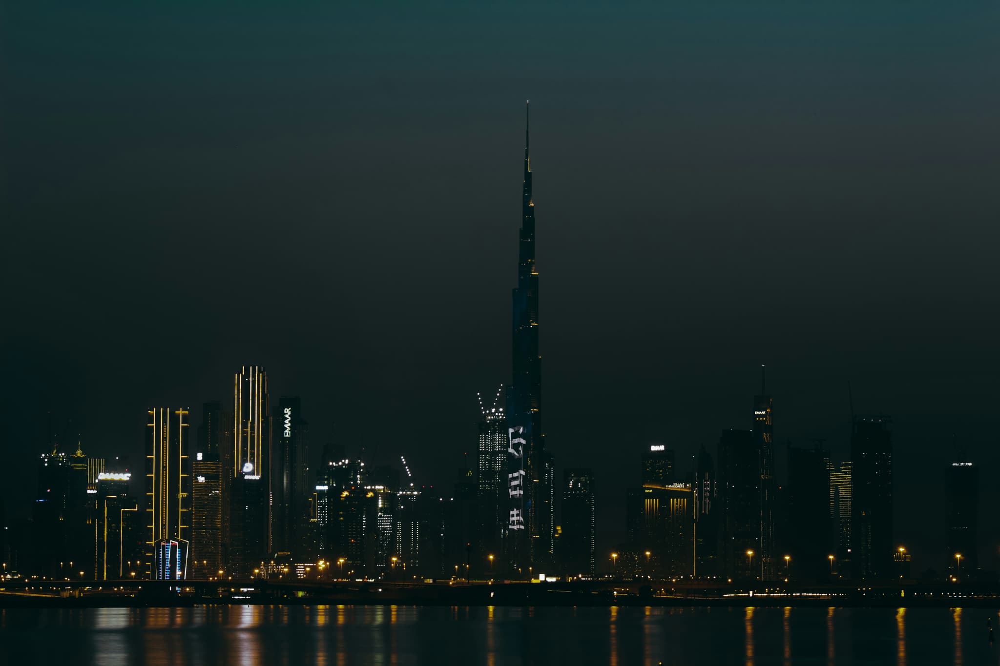 Dubai skyline at night with Burj Khalifa illuminated and city lights reflecting on the water