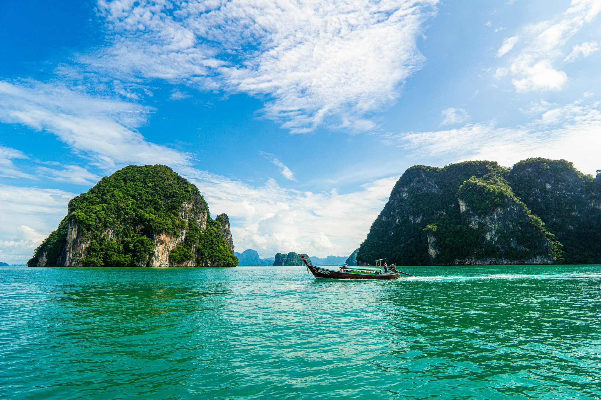 Krabi limestone karst cliffs rising from emerald green waters with long-tail boats